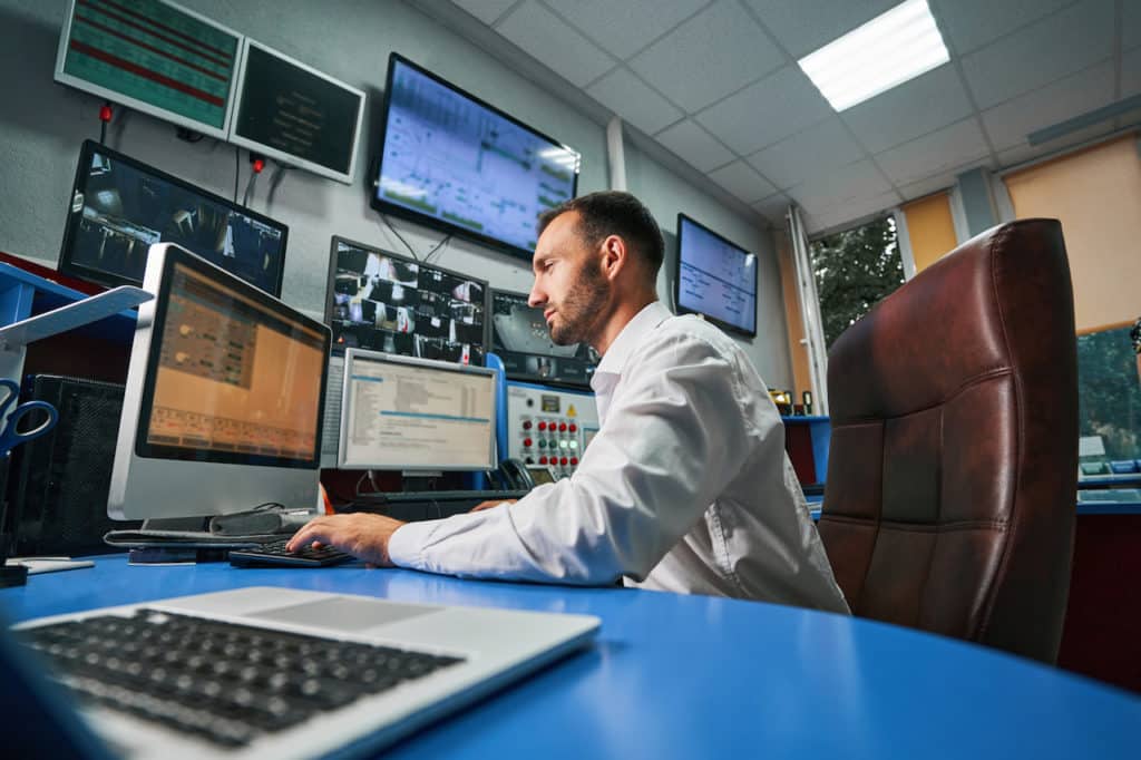 IT services professional working in office on computer with multiple screens