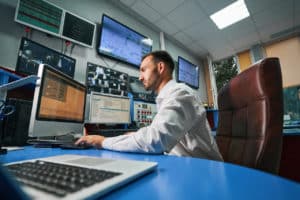 IT services professional working in an office on a computer with multiple screens