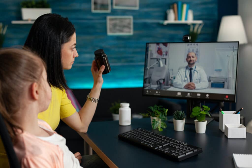 Doctor using technology in mental health work to talk to a mother and a daughter about mental health issues