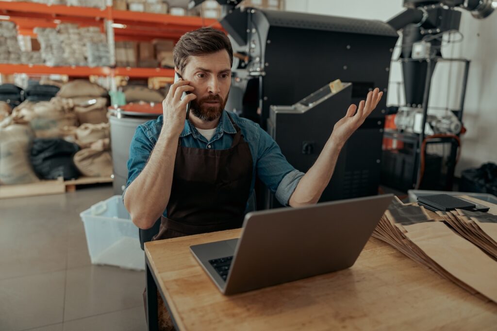 small business owner talking on the phone while looking at laptop